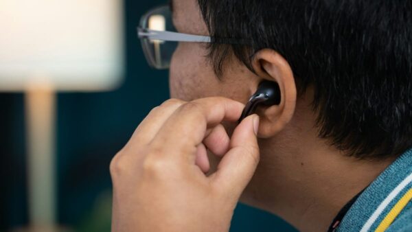 Tragekomfort von Earbuds beim Einsetzen ins Ohr Earbuds vs. In-Ear: Person setzt kabellosen Earbud ins Ohr ein