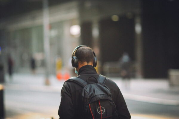 Noise-Cancelling Kopfhörer im Einsatz auf offener Straße Person mit Noise-Cancelling Kopfhörer im Straßenverkehr von hinten