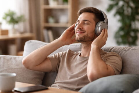 Mann hört entspannt Musik mit Over-Ear-Kopfhörern als Beispiel für ermüdungsfreien Klang